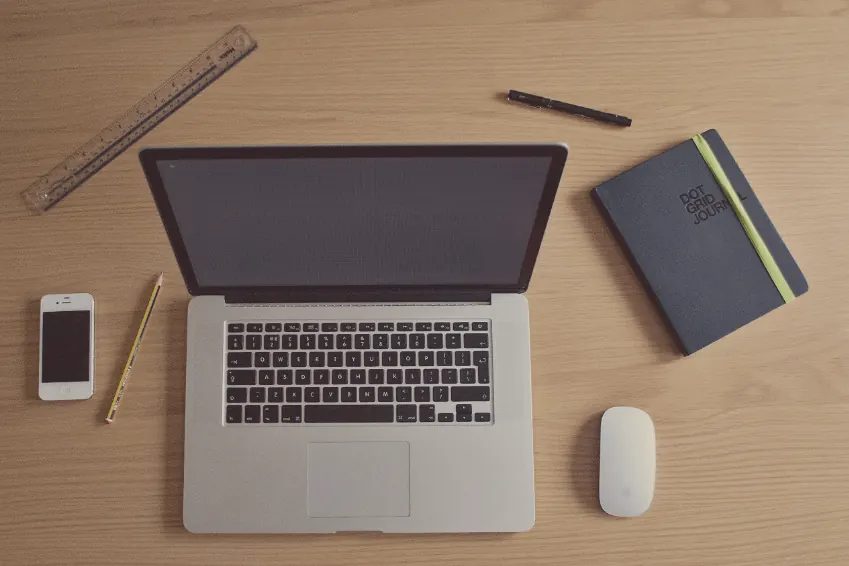 Vista cenital de un escritorio con portátil, móvil, cuaderno, regla y lápiz